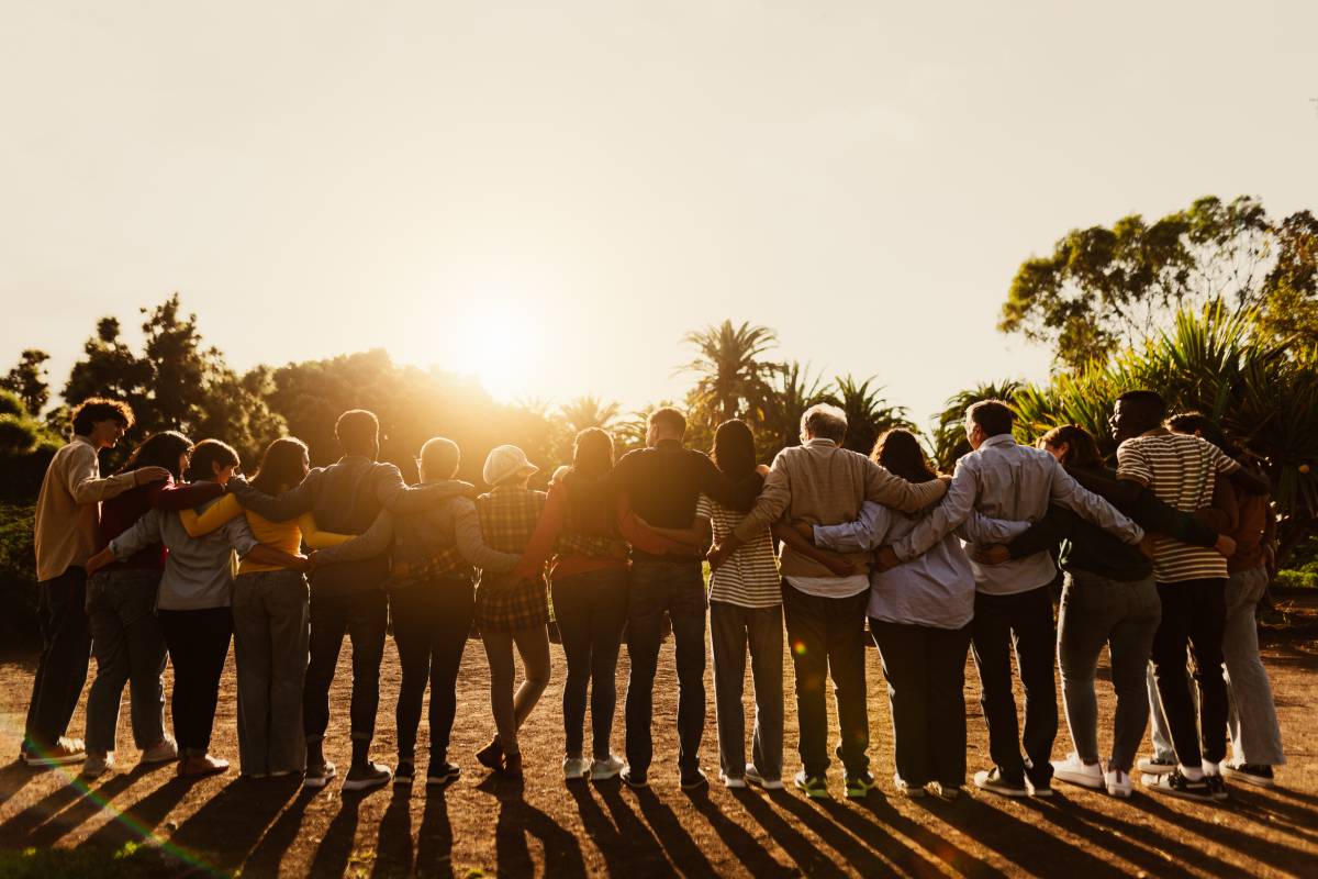 Back of giving circle community with arms wrapped around each other.